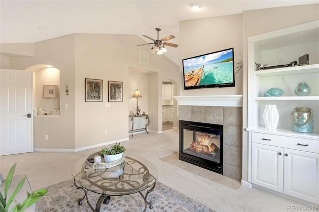 living room featuring light colored carpet, visible vents, a fireplace, and arched walkways