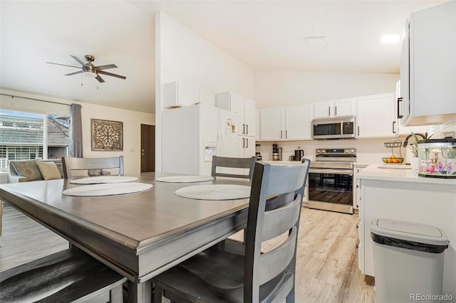 dining area with ceiling fan, sink, light hardwood / wood-style floors, and vaulted ceiling