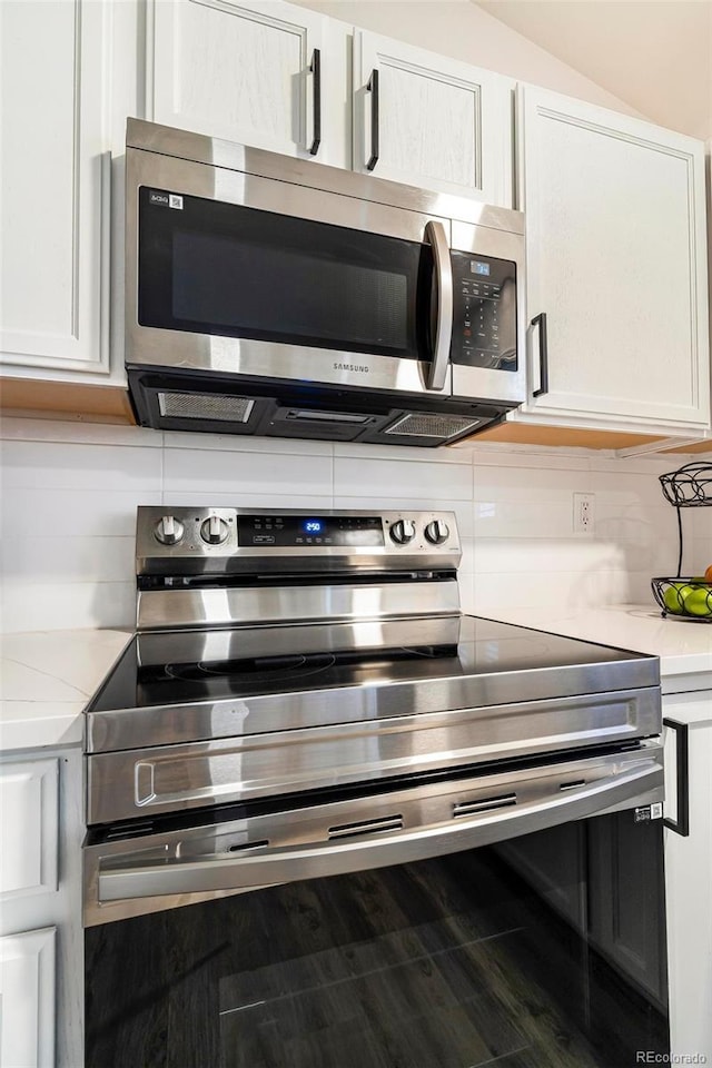 details with white cabinets, decorative backsplash, light stone countertops, and appliances with stainless steel finishes