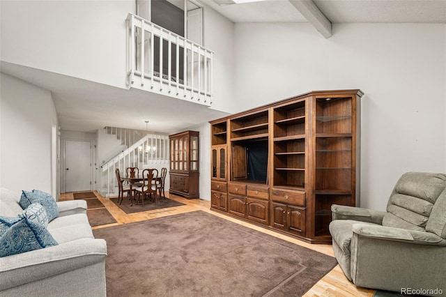 living room with wood finished floors, beam ceiling, stairs, and a towering ceiling