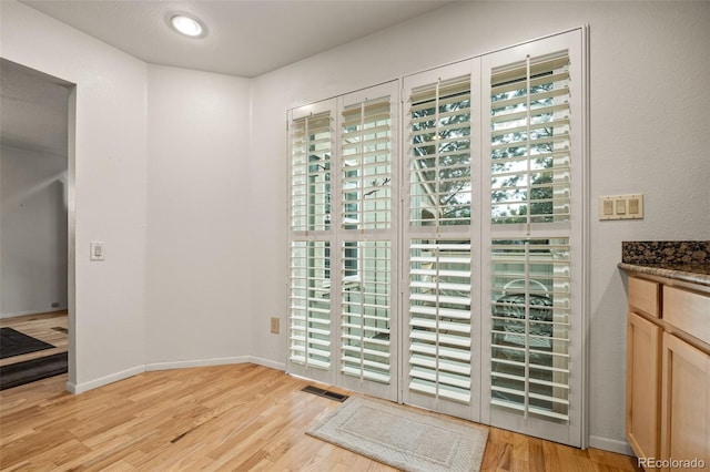 doorway to outside featuring light wood-style floors, healthy amount of natural light, and baseboards