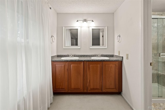 bathroom featuring a stall shower, double vanity, and a textured ceiling