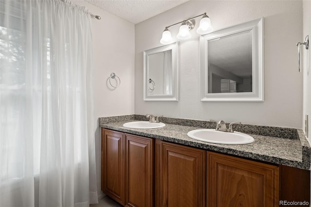 bathroom with a textured ceiling and double vanity