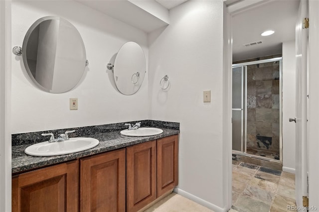 bathroom with baseboards, a shower stall, and double vanity