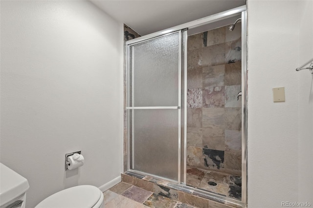 full bathroom with toilet, stone tile floors, a shower stall, and baseboards