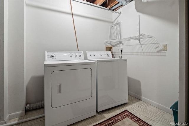 clothes washing area featuring washer and clothes dryer, baseboards, and light flooring