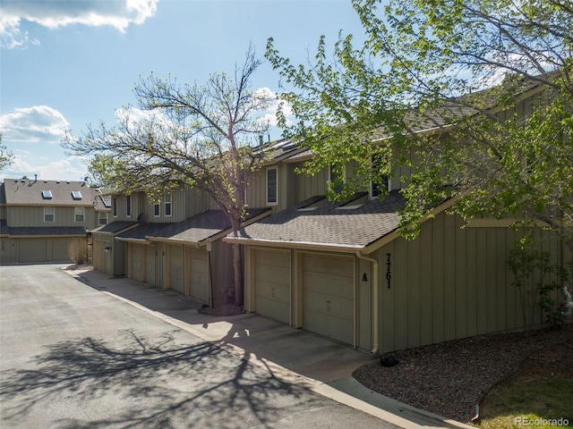 multi unit property featuring roof with shingles, an attached garage, and a residential view