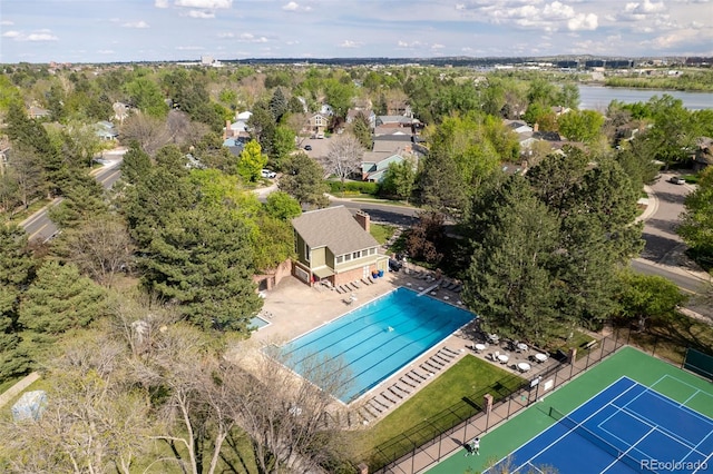 drone / aerial view of a pool area and a tree filled landscape