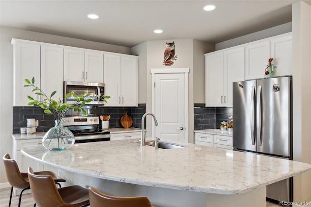 763 Sage Forest Ln, Monument, CO 80132 - kitchen with appliances with stainless steel finishes, a sink, white cabinetry, a kitchen bar, and recessed lighting