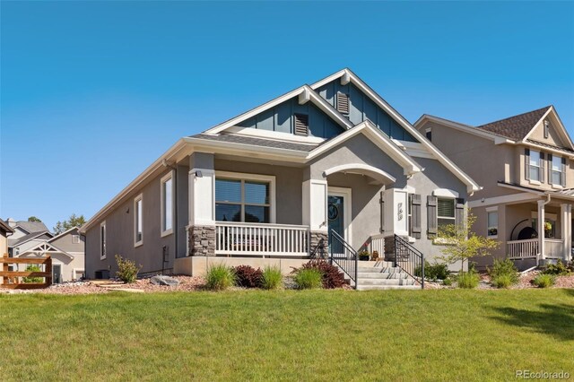763 Sage Forest Ln, Monument, CO 80132 - craftsman-style home featuring covered porch, stucco siding, a front lawn, and board and batten siding