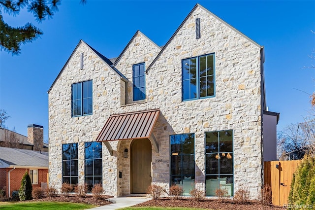 view of front facade with stone siding and fence