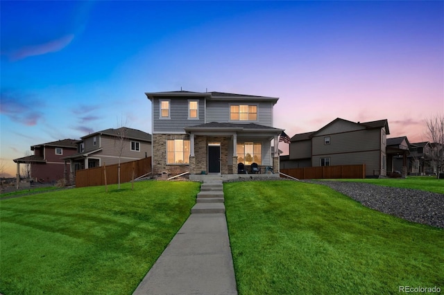 view of front of property with stone siding, a porch, a front lawn, and fence