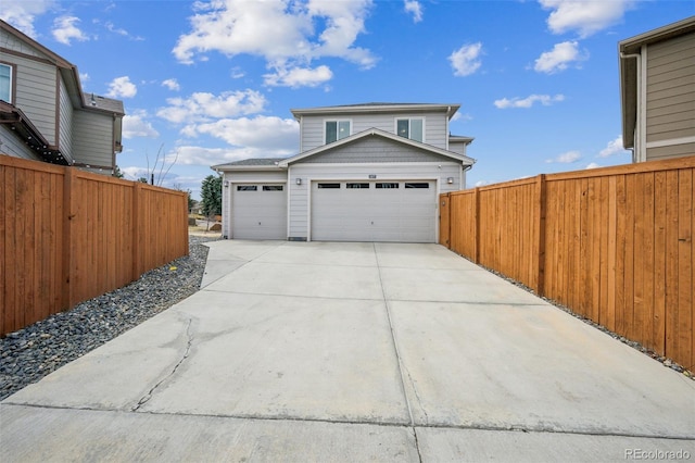 garage with concrete driveway and fence