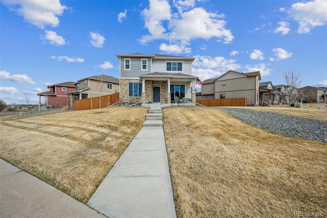 view of front of home with a residential view, stone siding, covered porch, and fence