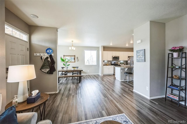 entryway featuring baseboards, an inviting chandelier, and dark wood-style flooring