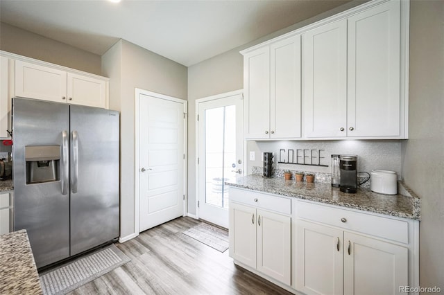 kitchen featuring light wood-style flooring, light stone countertops, white cabinets, and stainless steel fridge with ice dispenser