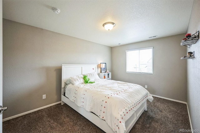 bedroom featuring visible vents, a textured ceiling, baseboards, and dark colored carpet