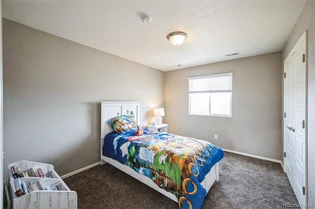 carpeted bedroom featuring visible vents, baseboards, and a textured ceiling
