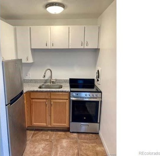 kitchen with light stone countertops, white cabinetry, appliances with stainless steel finishes, and sink