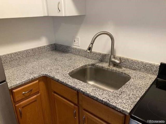 kitchen with electric stove, sink, and light stone counters