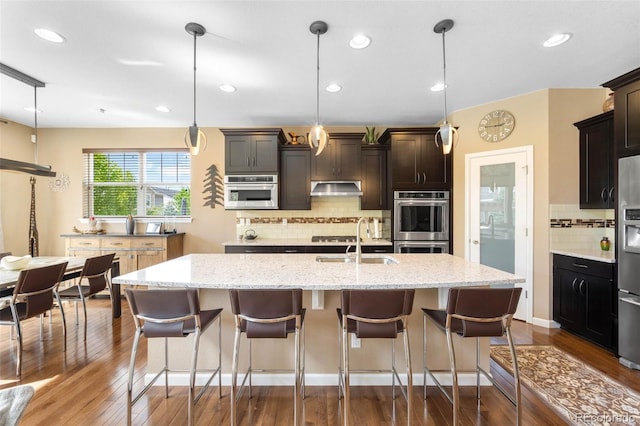10057 Des Moines St, Parker, CO 80134 - kitchen featuring a sink, backsplash, dark wood-style flooring, an island with sink, and recessed lighting