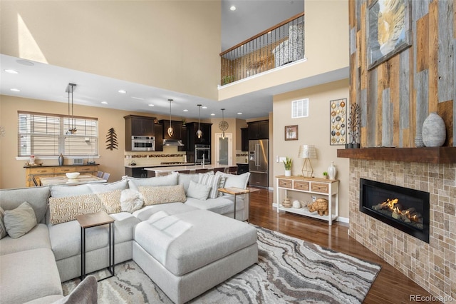 10057 Des Moines St, Parker, CO 80134 - living area featuring a towering ceiling, wood finished floors, a tiled fireplace, recessed lighting, and baseboards