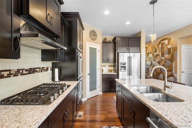 10057 Des Moines St, Parker, CO 80134 - kitchen with stainless steel appliances, a sink, dark wood-style flooring, tasteful backsplash, and light stone countertops