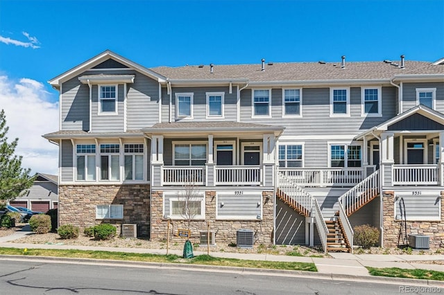 view of property featuring stone siding, covered porch, and central air condition unit