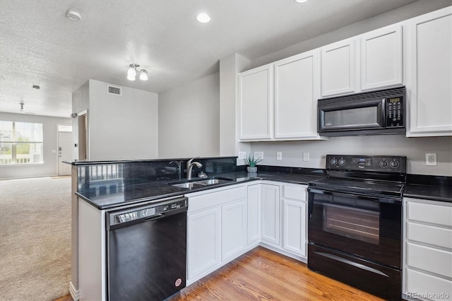 kitchen featuring black appliances, a sink, open floor plan, a peninsula, and white cabinets