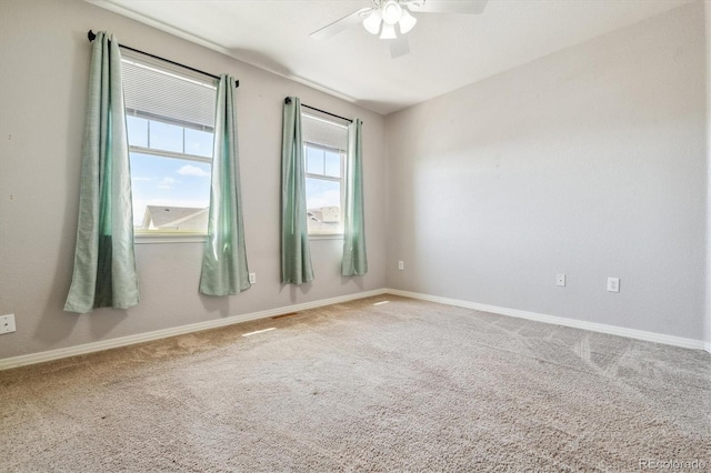 carpeted spare room with ceiling fan and baseboards