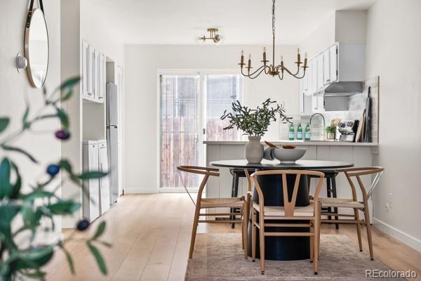 dining space with light wood-style flooring, a chandelier, and baseboards