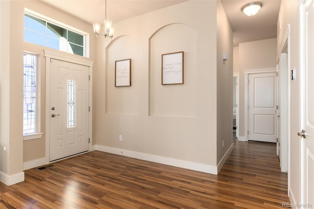 foyer entrance with dark hardwood / wood-style floors and an inviting chandelier