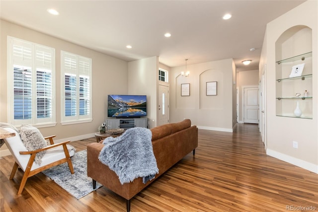 living room featuring hardwood / wood-style flooring, built in shelves, and a notable chandelier