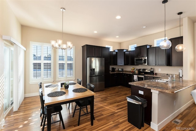 kitchen featuring decorative light fixtures, kitchen peninsula, sink, and stainless steel appliances