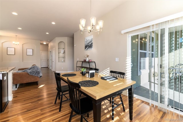 dining room with built in features, hardwood / wood-style flooring, and a notable chandelier