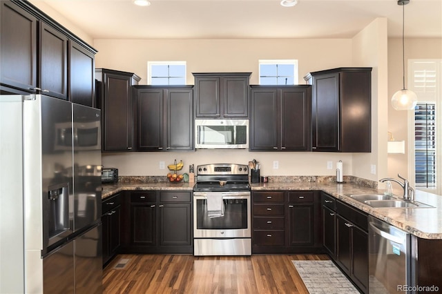 kitchen featuring stainless steel appliances, decorative light fixtures, dark wood-type flooring, a wealth of natural light, and sink