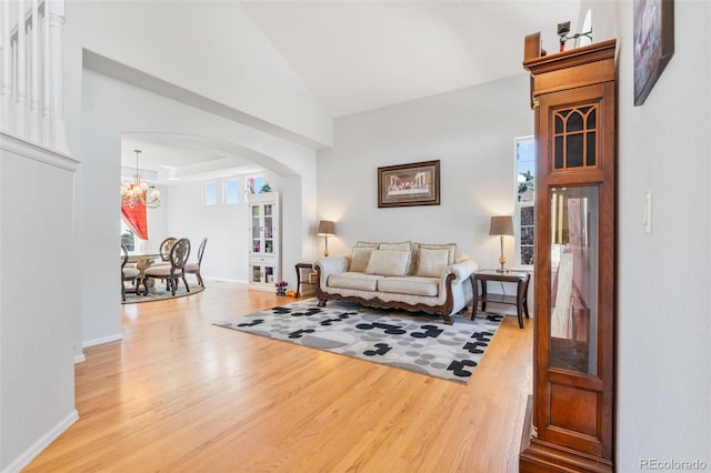 24022 E Jamison Dr, Aurora, CO 80016 - living room featuring arched walkways, light wood-style floors, a chandelier, high vaulted ceiling, and baseboards