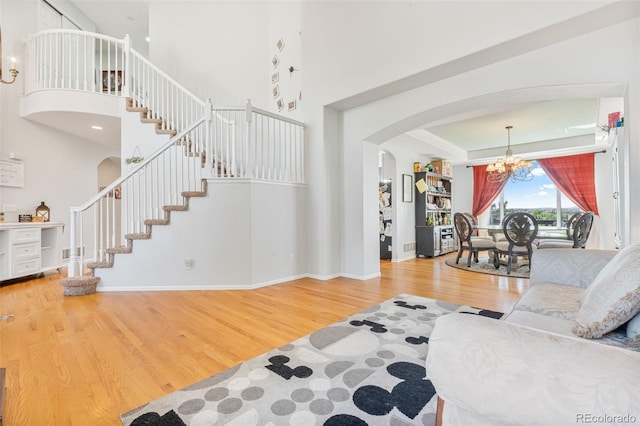 24022 E Jamison Dr, Aurora, CO 80016 - living area featuring arched walkways, a chandelier, stairs, wood finished floors, and a towering ceiling