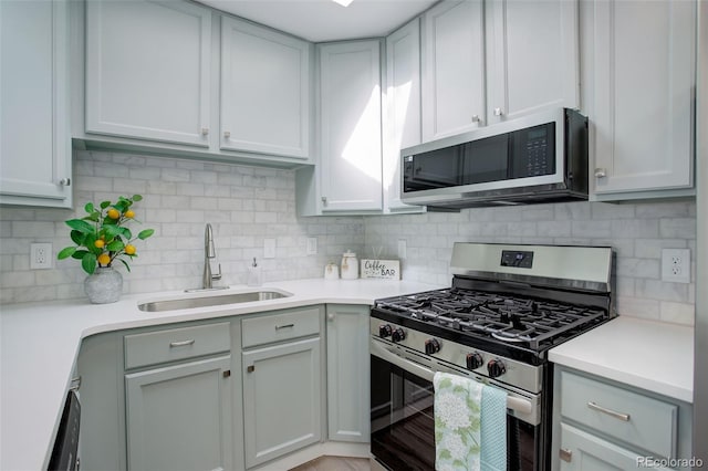 kitchen featuring tasteful backsplash, appliances with stainless steel finishes, light countertops, and a sink