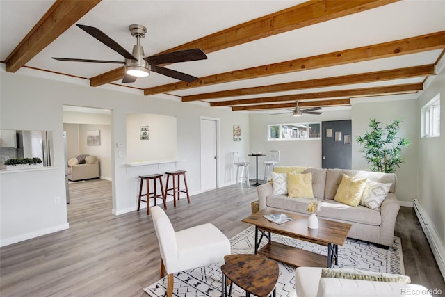 living area featuring a baseboard heating unit, ceiling fan, wood finished floors, and a wealth of natural light