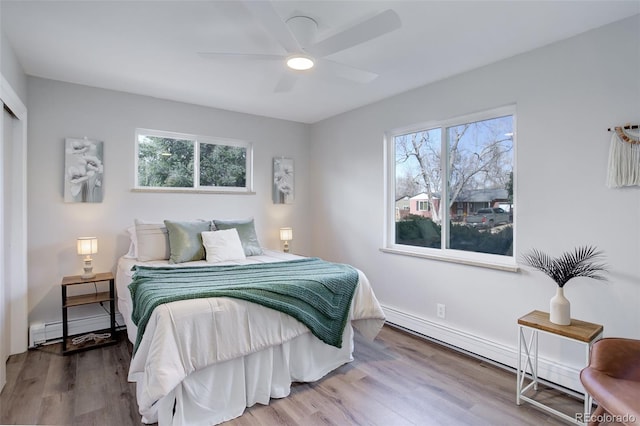 bedroom featuring a baseboard heating unit, a ceiling fan, and wood finished floors