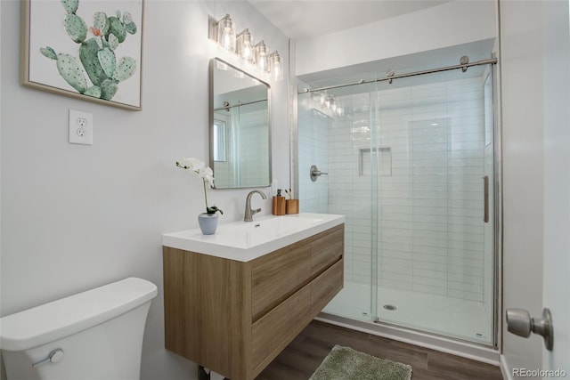 full bathroom featuring toilet, a shower stall, wood finished floors, and vanity