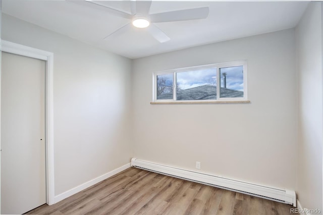 spare room featuring light wood-style floors, a baseboard radiator, ceiling fan, and baseboards