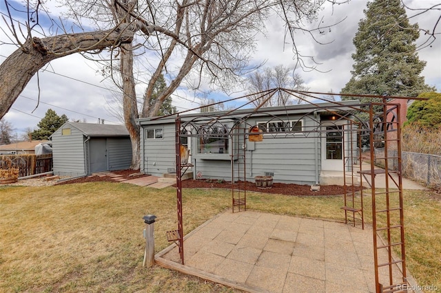 rear view of property featuring entry steps, a patio, a yard, fence, and an outdoor structure