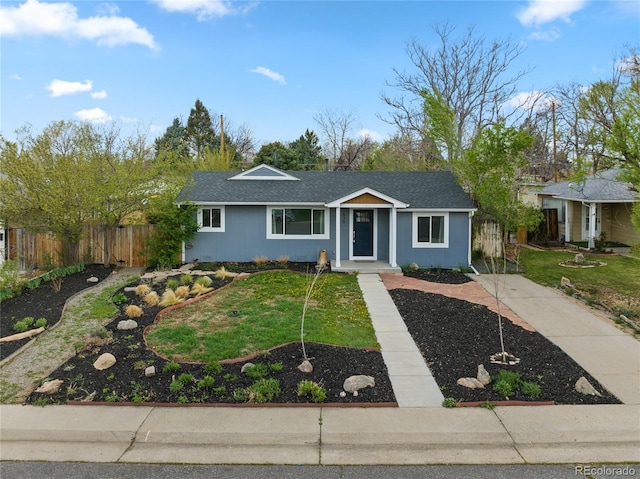 view of front of property with fence, a front lawn, and roof with shingles