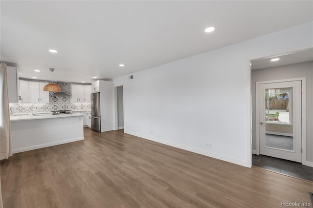 unfurnished living room with baseboards, wood finished floors, and recessed lighting