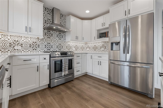 kitchen with light countertops, wall chimney range hood, appliances with stainless steel finishes, and white cabinets