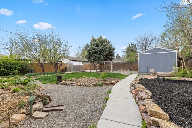 view of yard featuring a fenced backyard, an outdoor structure, and a greenhouse