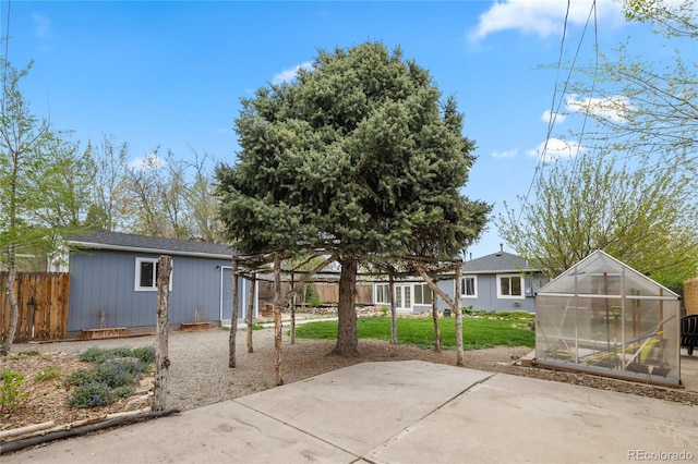 back of property with an exterior structure, fence, a patio area, an outdoor structure, and a yard