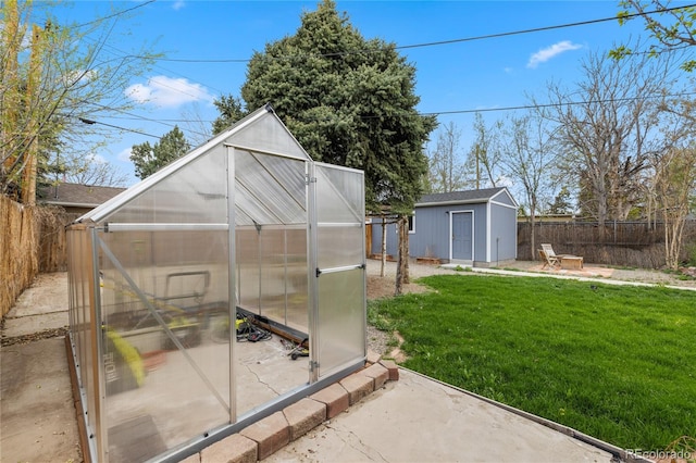 view of greenhouse with a lawn and a fenced backyard